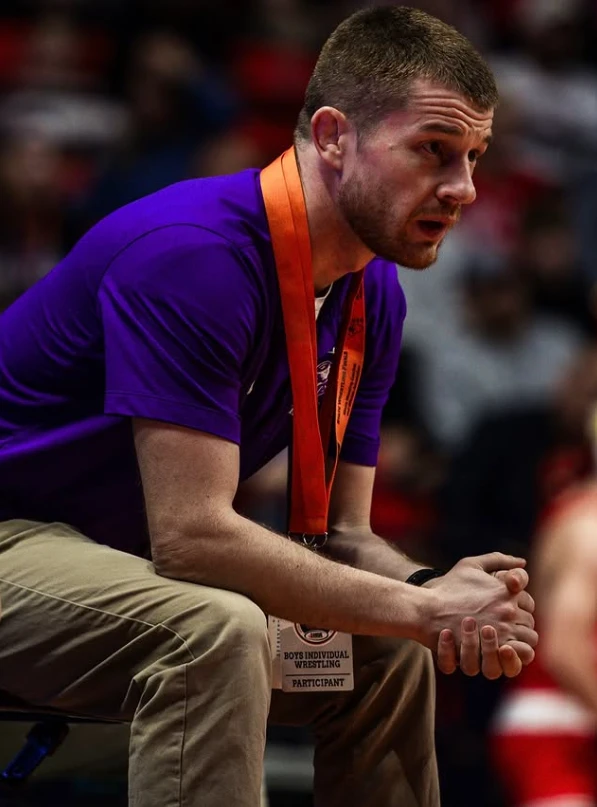 A Baker Bros coach watching a match from the edge of the mat